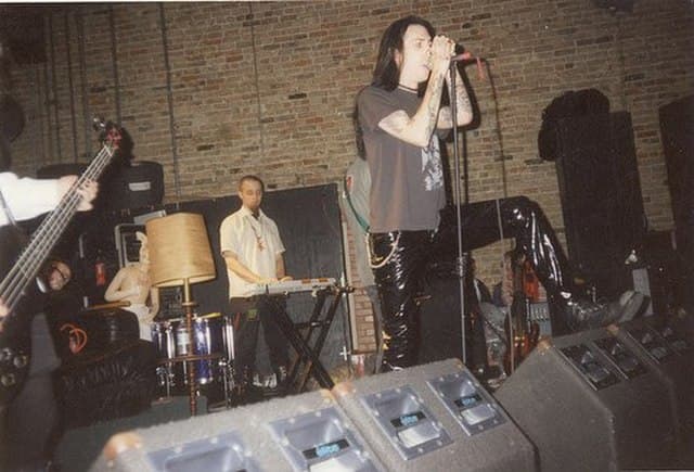 Vintage image of Marilyn Manson performing in an underground club wearing a T-shirt, capturing his early raw shock rock era before fame.